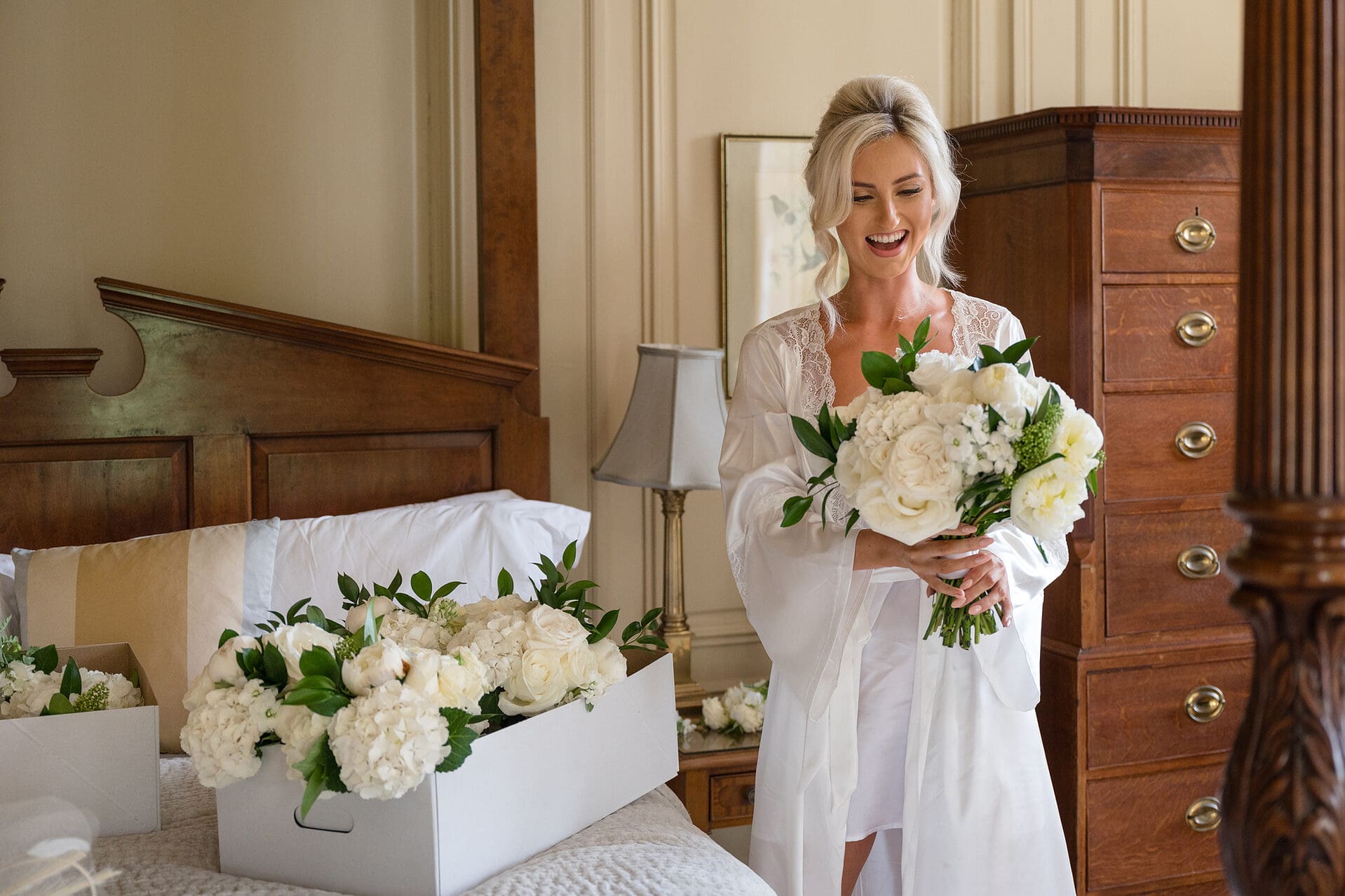 Bride wearing a white robe and admiring her wedding bouquet