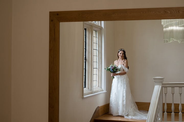Reflection of the bride in a mirror at the top of the staircase at Notley Abbey
