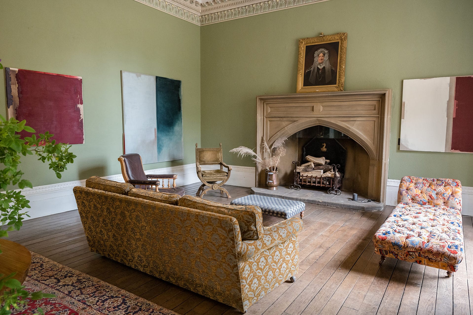 The entrance hall at Keythorpe Manor with a huge fireplace, sofas, period portraits, and modern art