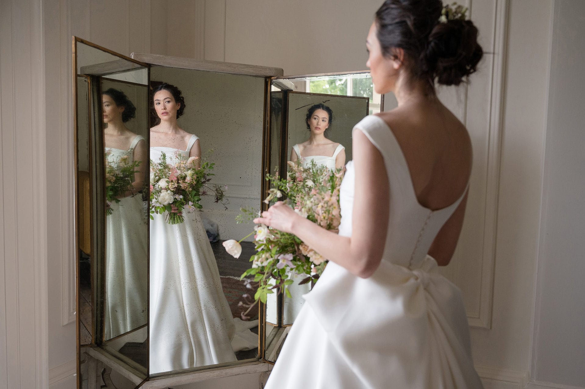 A three-piece mirror with a reflection of a bride in each piece