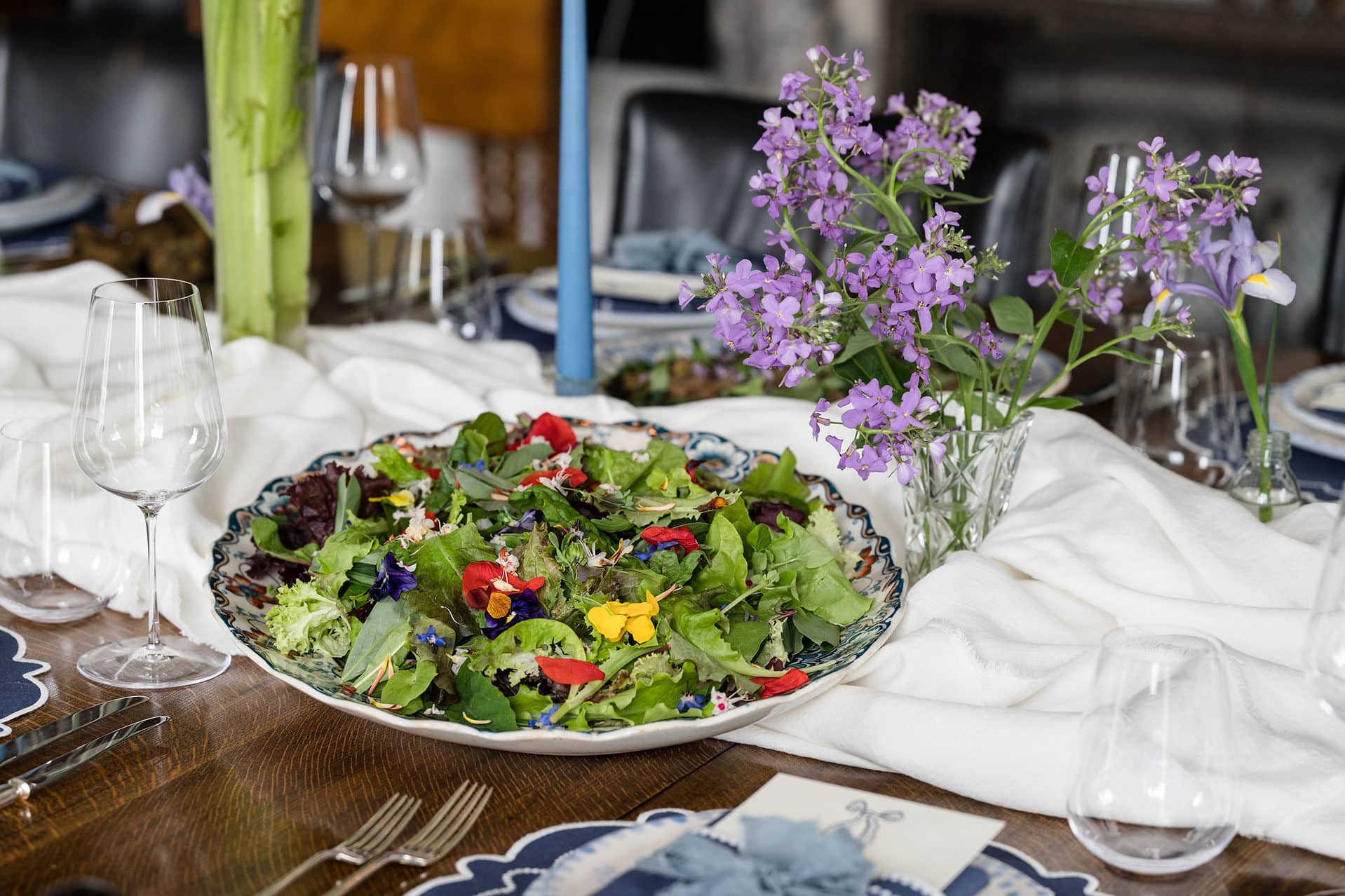 A fresh salad finished off with edible flowers served in an antique scallop edge serving bowl