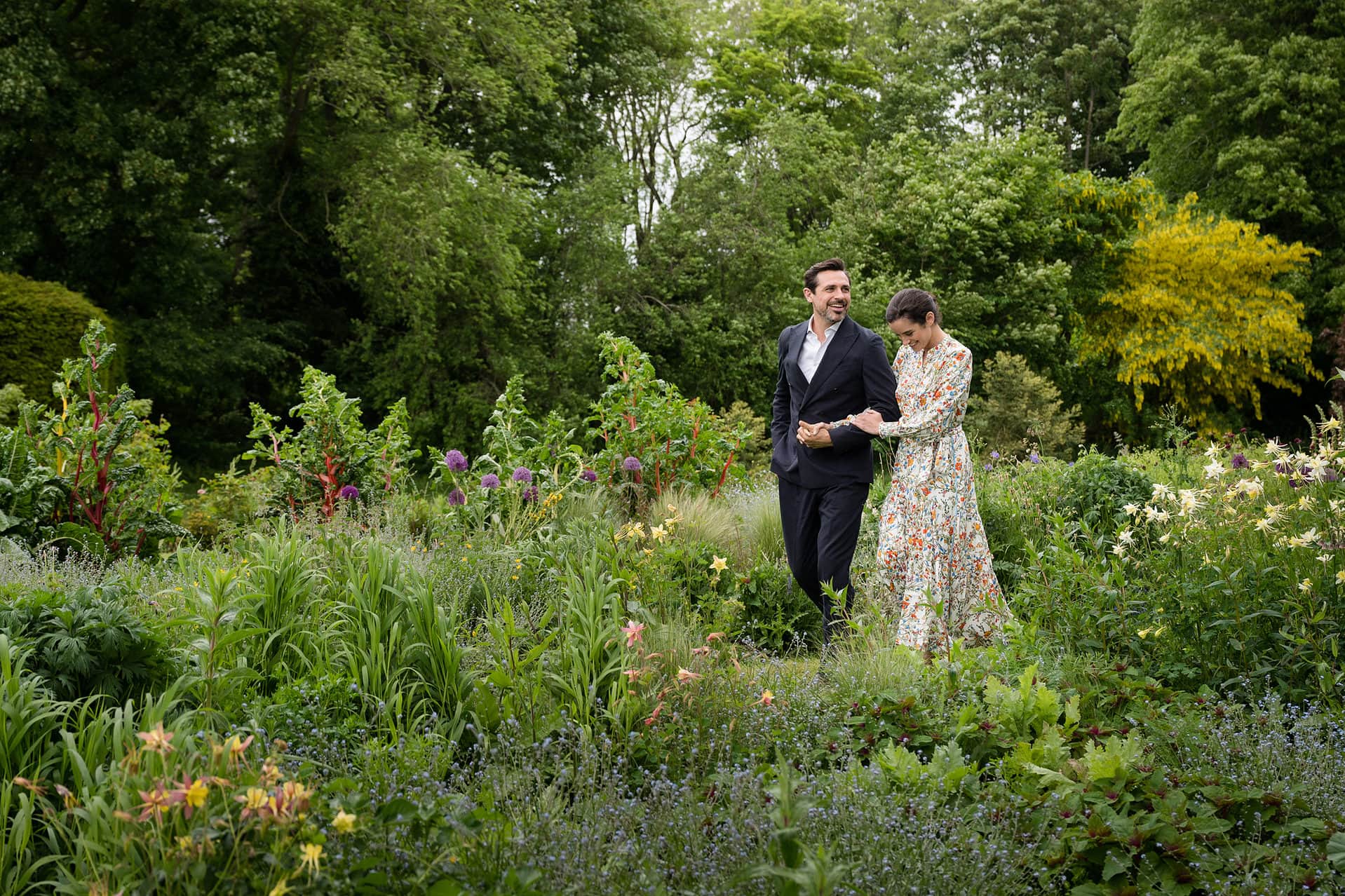A newly married couple walking arm-in-arm through the flowering gardens at Keythorpe Manor