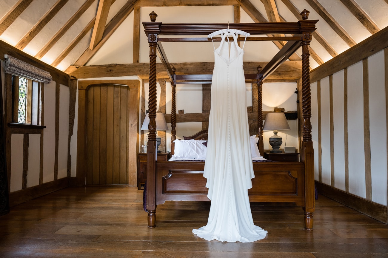 The bride's dress hanging from a four-poster wooden bed