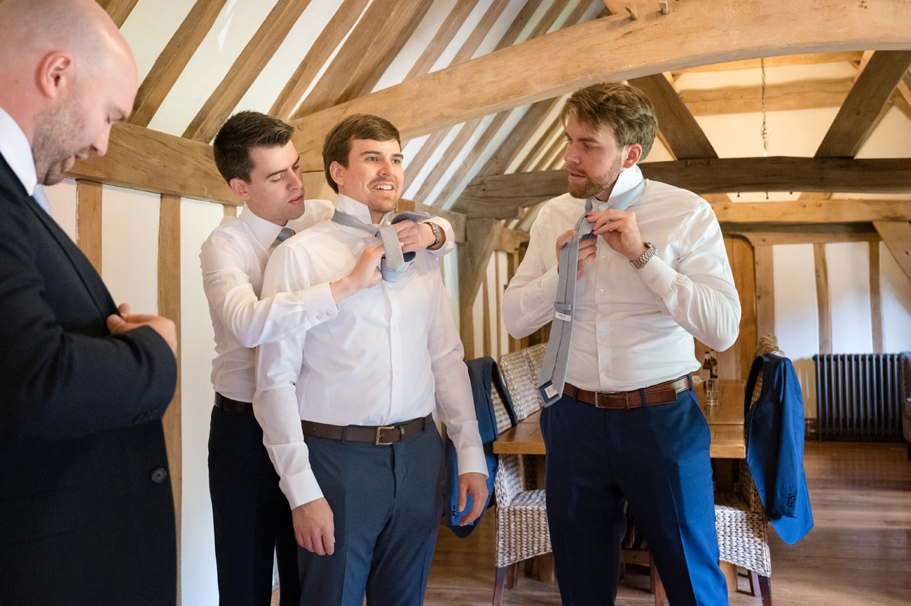 The groom helping his ushers to put their ties on