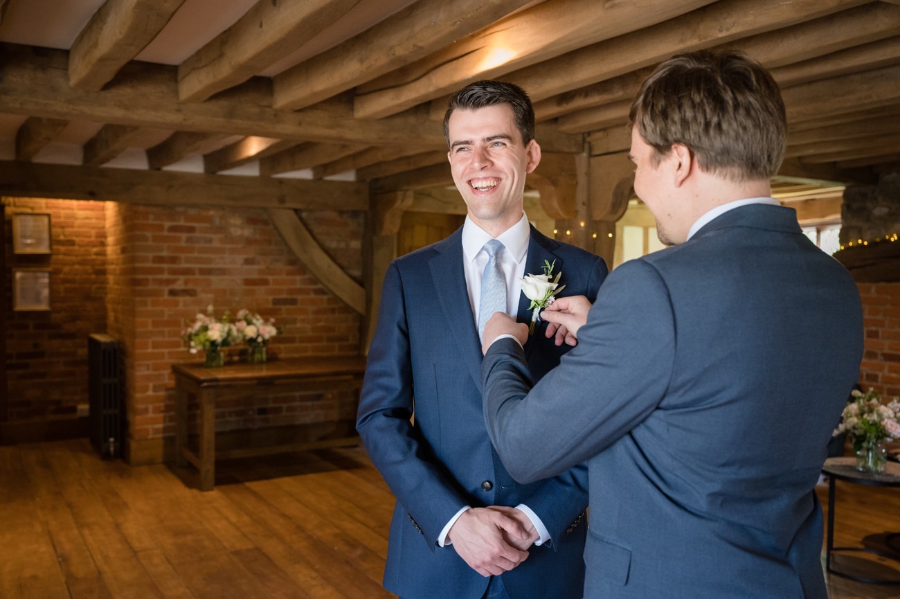 An usher pinning the groom's buttonhole onto his jacket