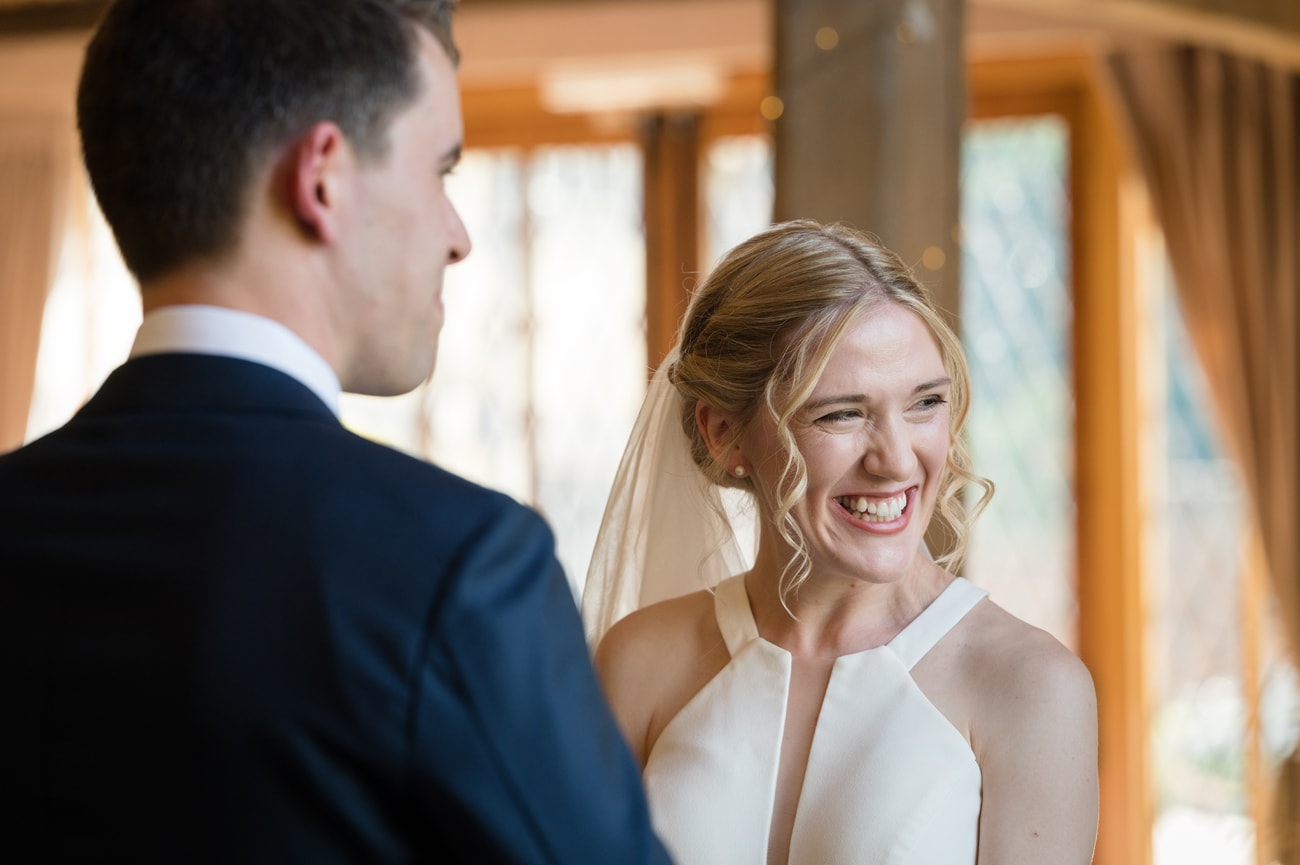 Bride smiling a really big cheesey grin as the groom says his marriage vows