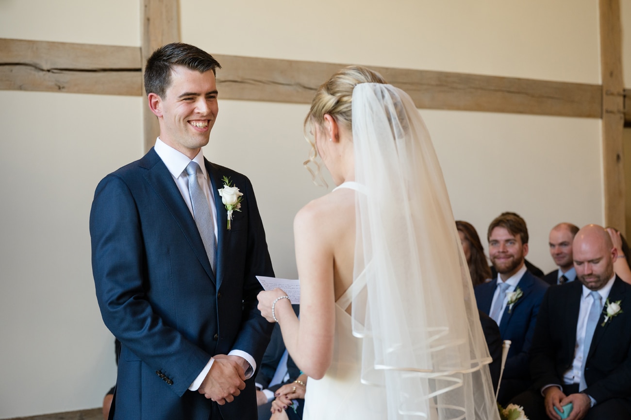The groom smiling at the bride as she says her vows to him