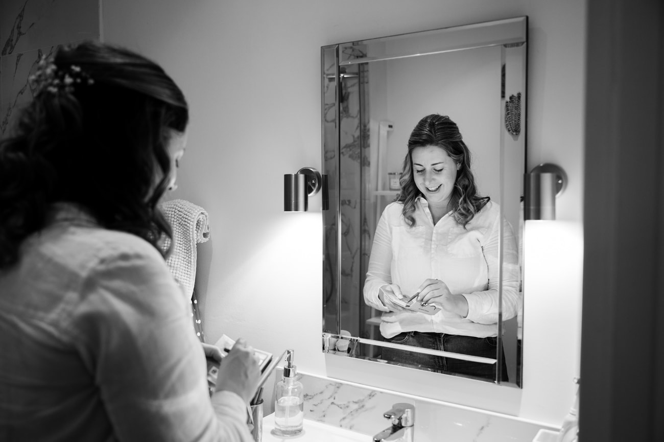 Bride doing her own makeup in a bathroom mirror