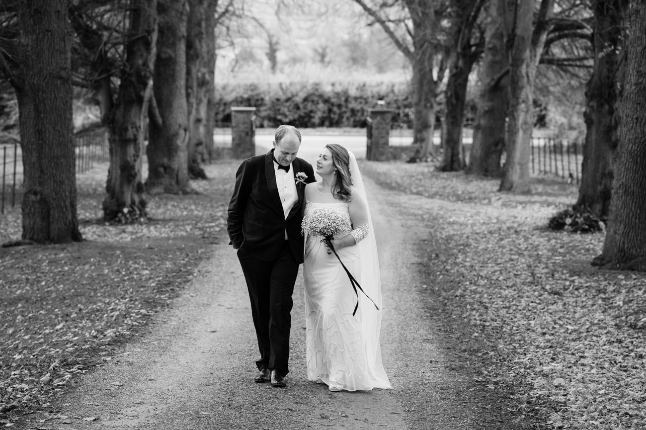 Bride and groom walking down the tree-lined driveway at Plum Park Manor