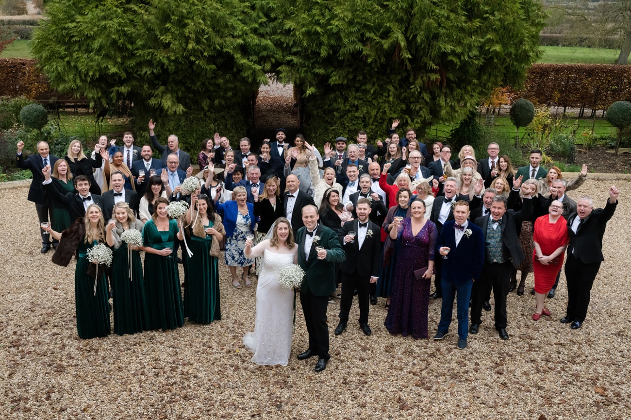 A big group photo taken from an upstairs window of all the wedding guests at the front entrance to Plum Park Manor
