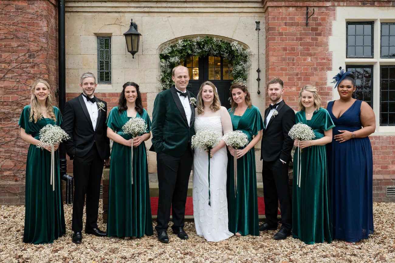 A group photo of the bride, groom, bridesmaids and best men in front of Plum Park Manor