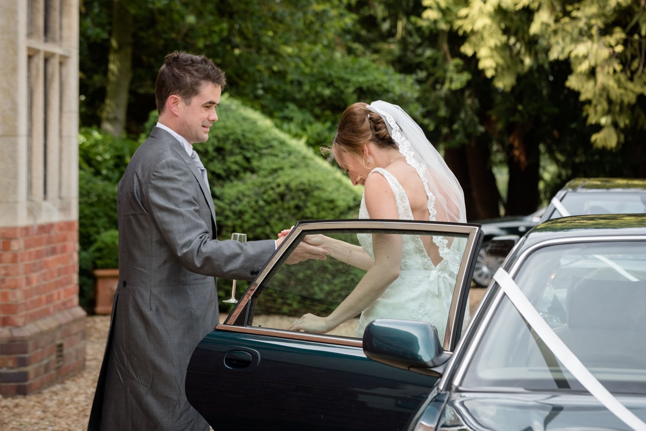 Groom helping bride out of the wedding car