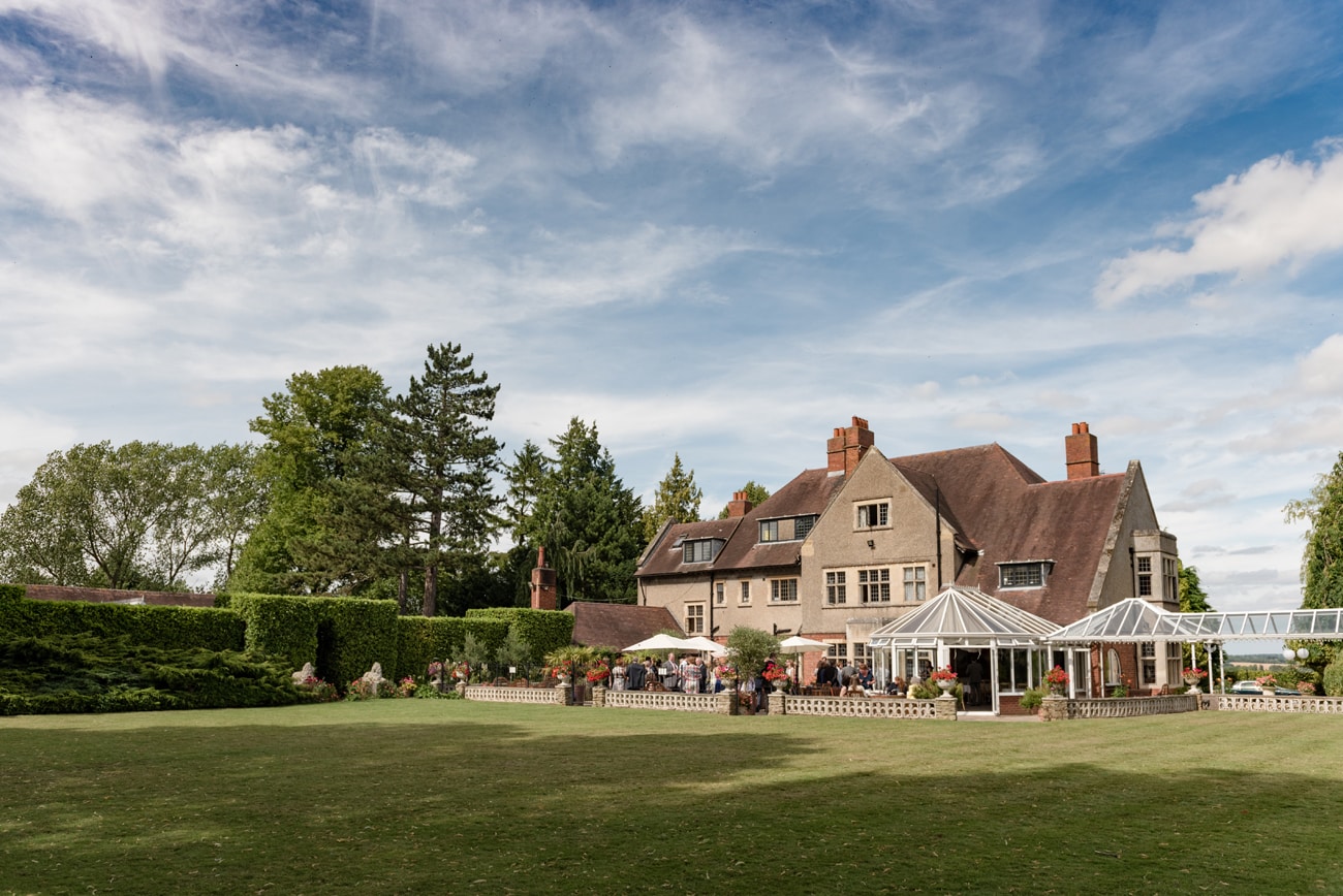 The back view of Plum Park Manor with a wedding drinks reception on the terrace