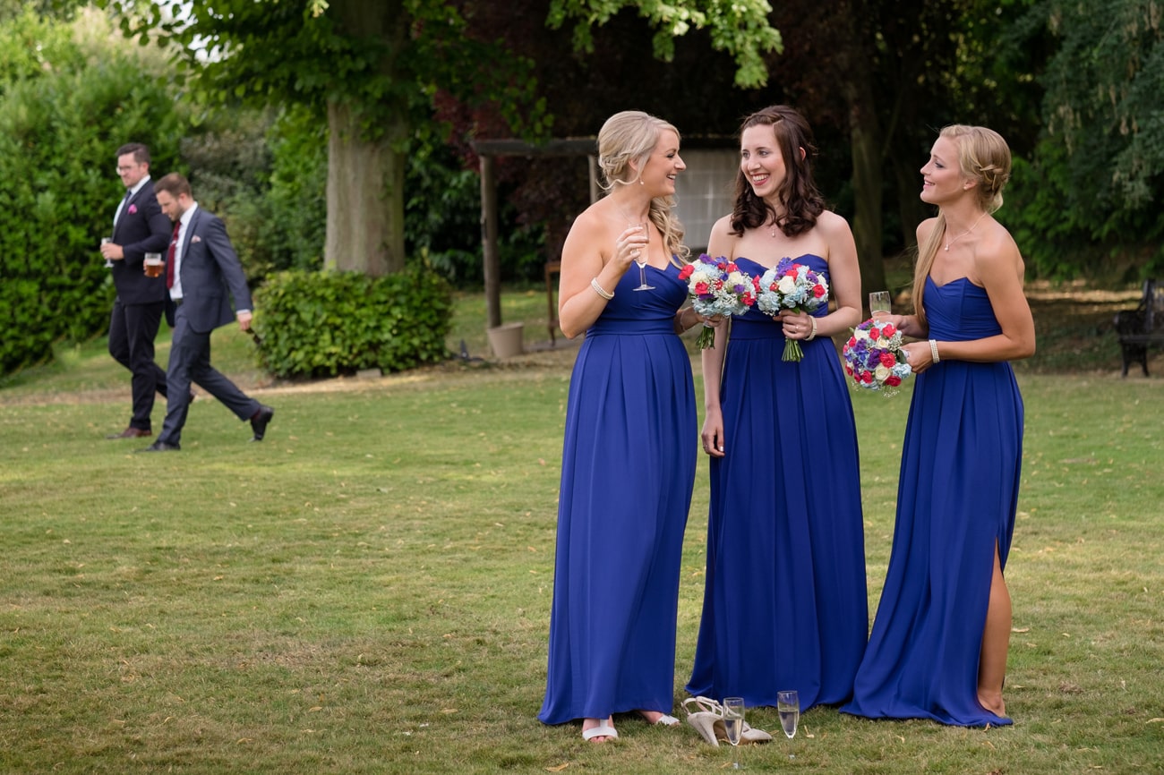 Three bridesmaids wearing royal blue dresses and chatting together