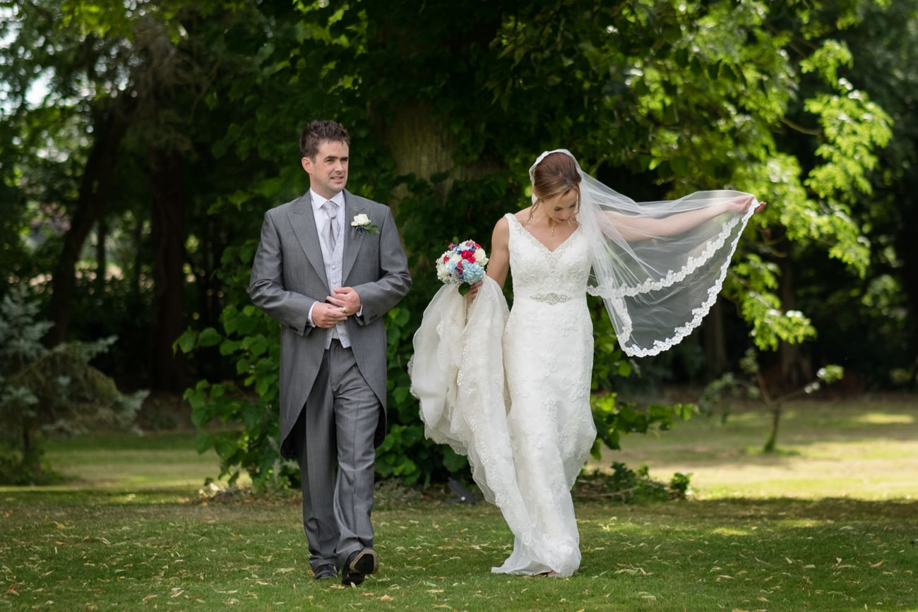 Bride and groom walking through the gardens at Plum Park Manor