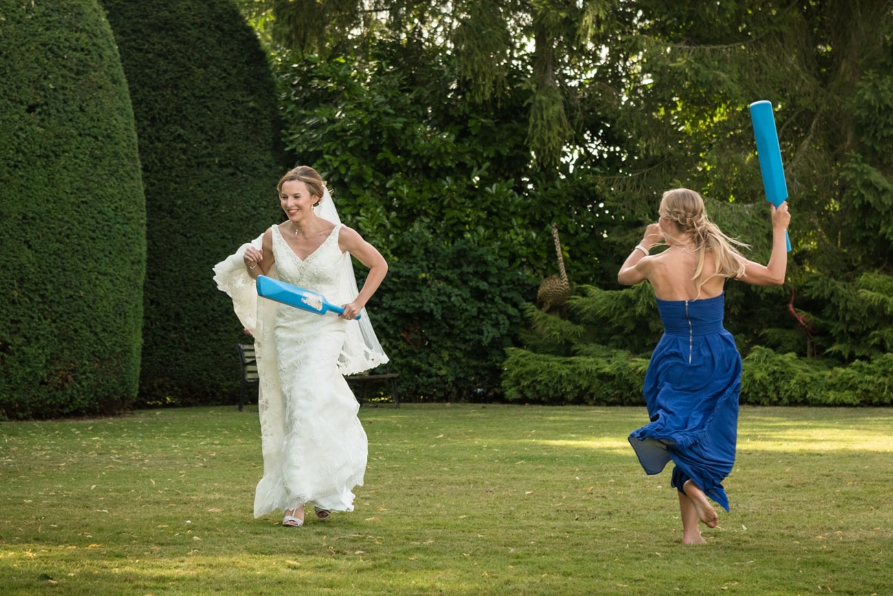 Bride and her bridesmaid running with cricket bats