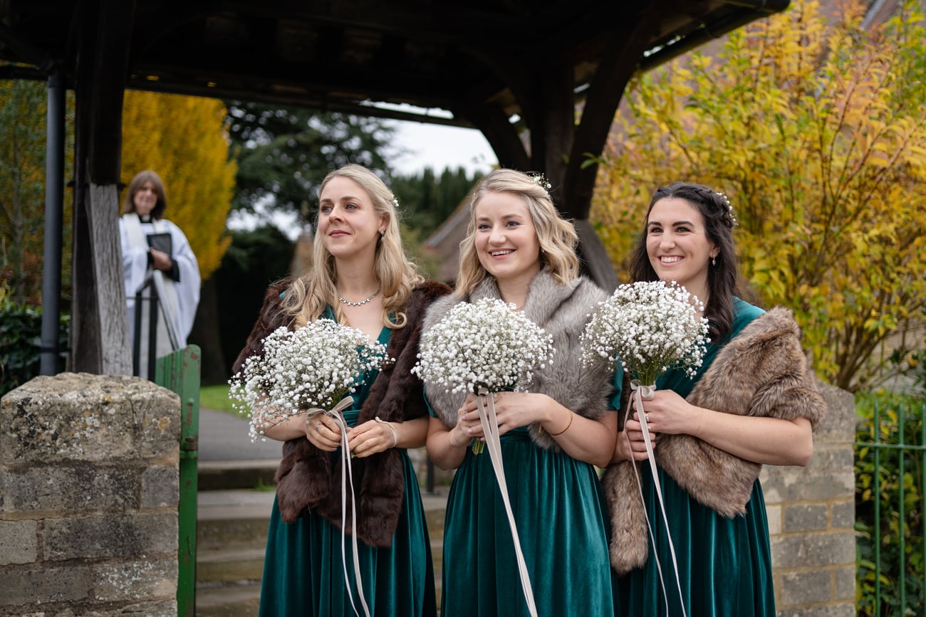 Bridesmaids waiting by the lych gate at St Michael's church in Silverstone for the bride to arrive