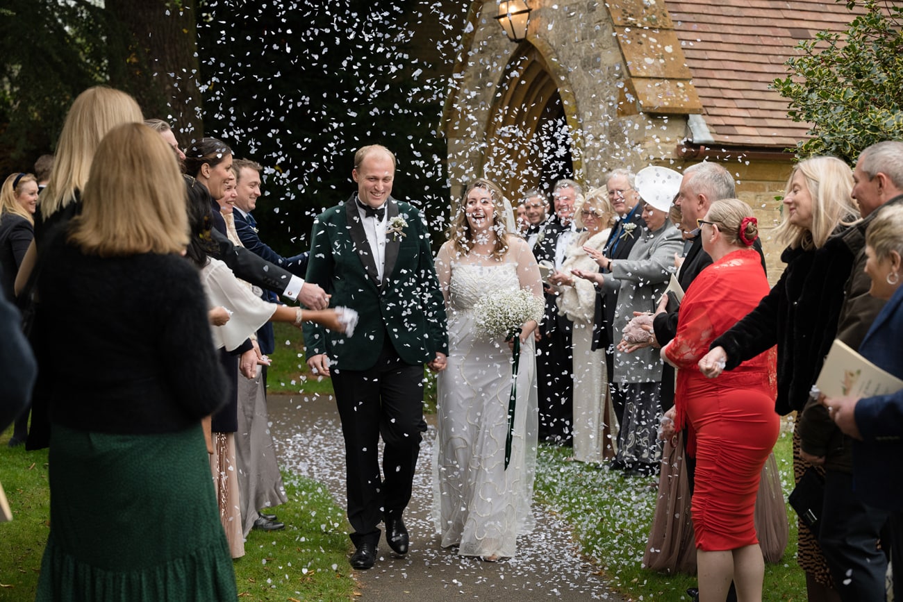 Wedding guests throwing confetti over bride and groom at St Michael's church in Silverstone