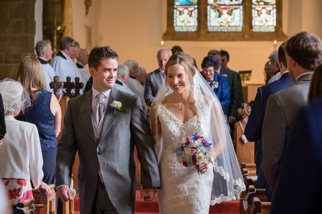 Bride and groom walking down the aisle at St Peter's church in Weston Favell
