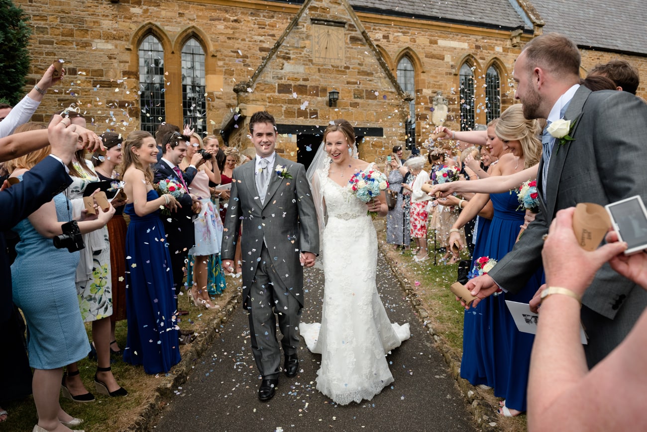 Guests throwing confetti over the bride and groom at St Peter's church in Weston Favell