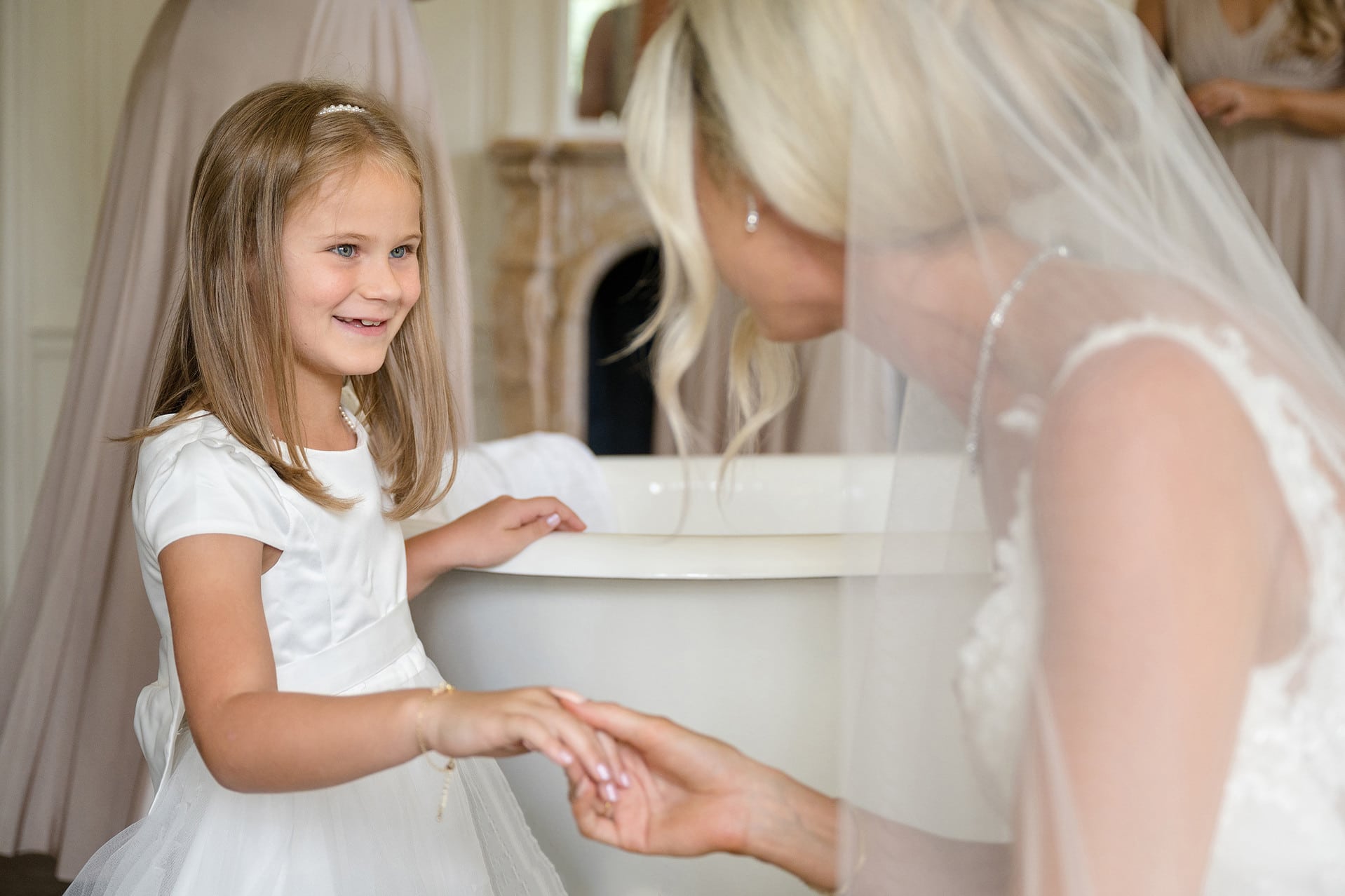 Bride holding her flower girl's hand to see her new bracelet