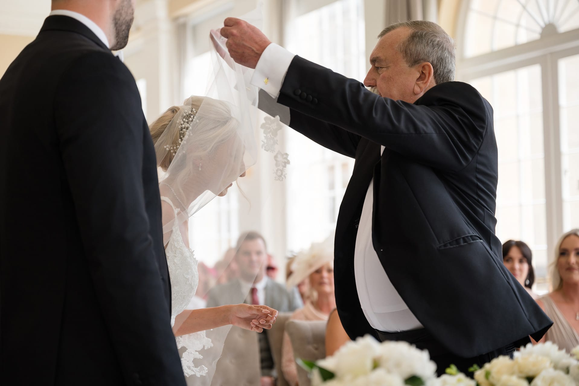 Father of the bride lifting bride's veil