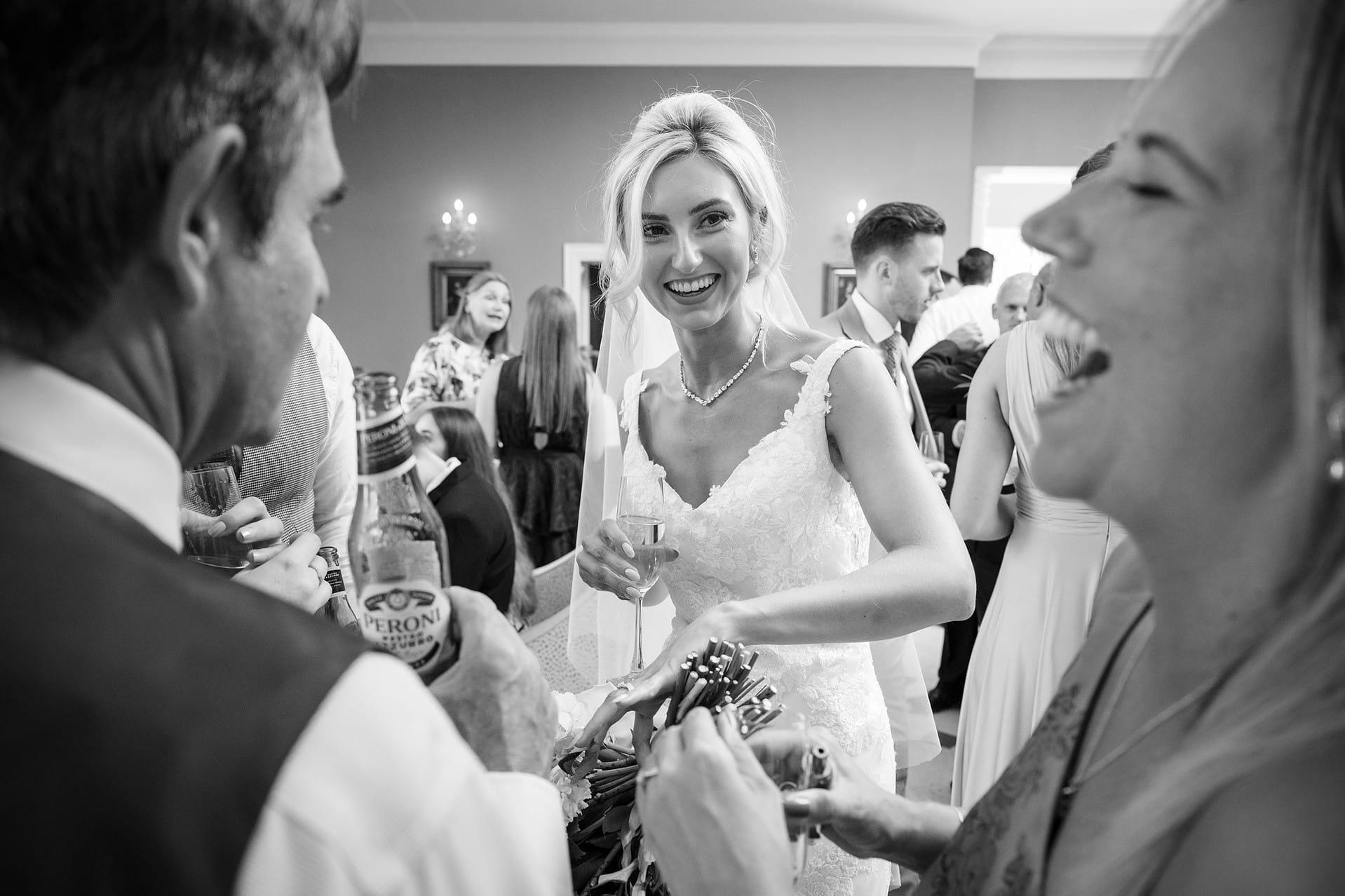 Bride laughing with her wedding guests as they check out her wedding ring
