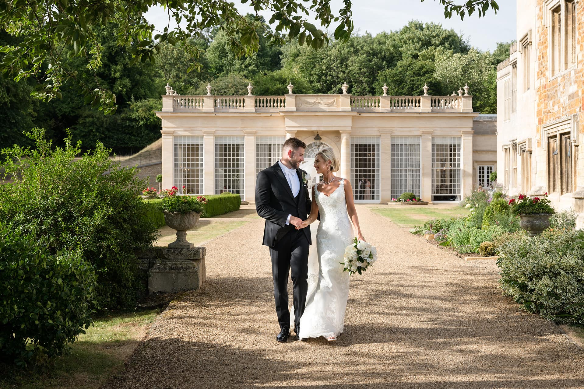Bride and groom walking in front of an orangery