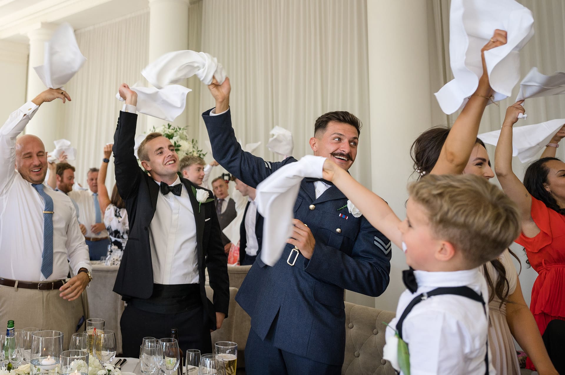 Wedding guests waving their napkins in the air as the bride and groom are announced in for the wedding breakfast