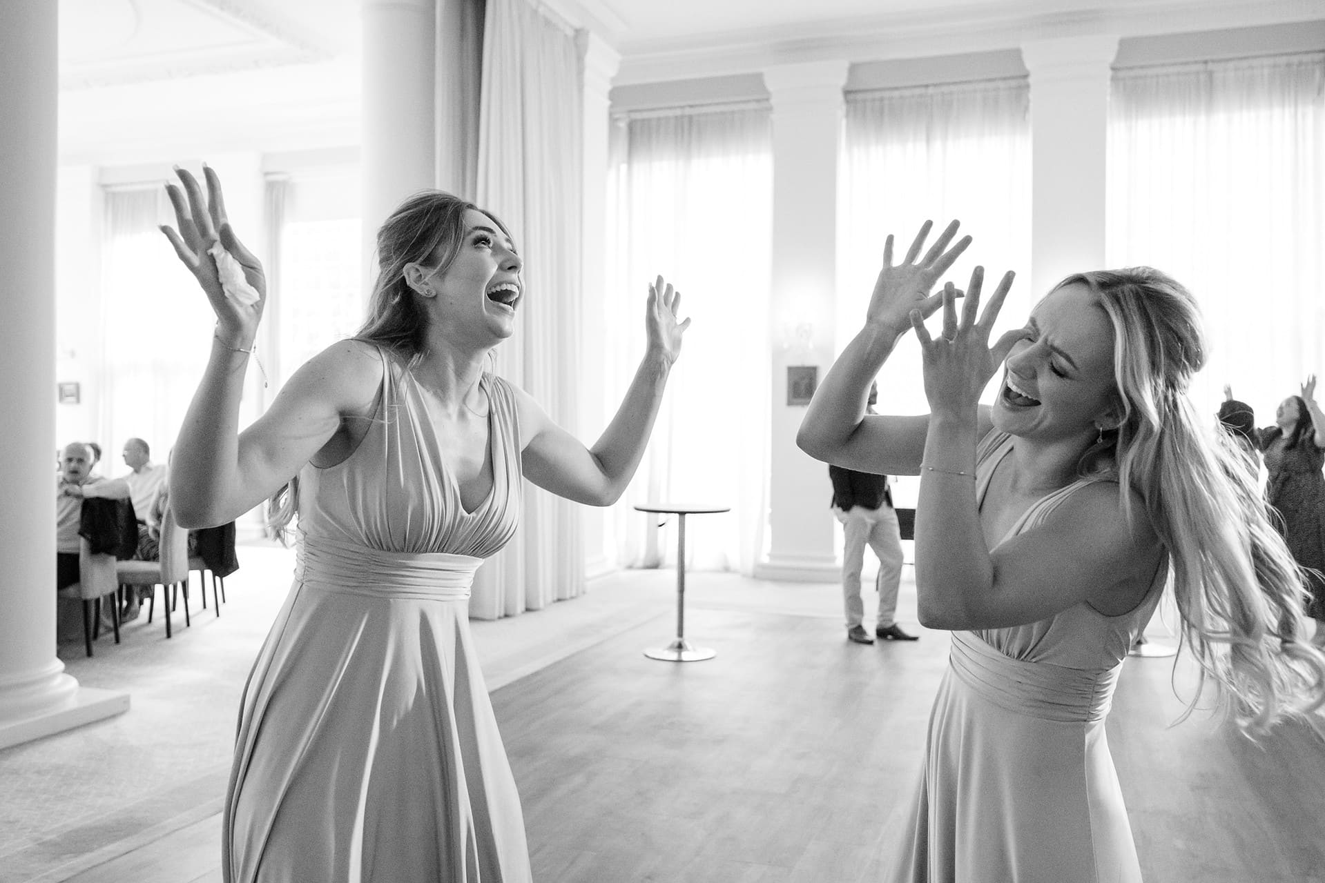 Two bridesmaids dancing with their hands in the air