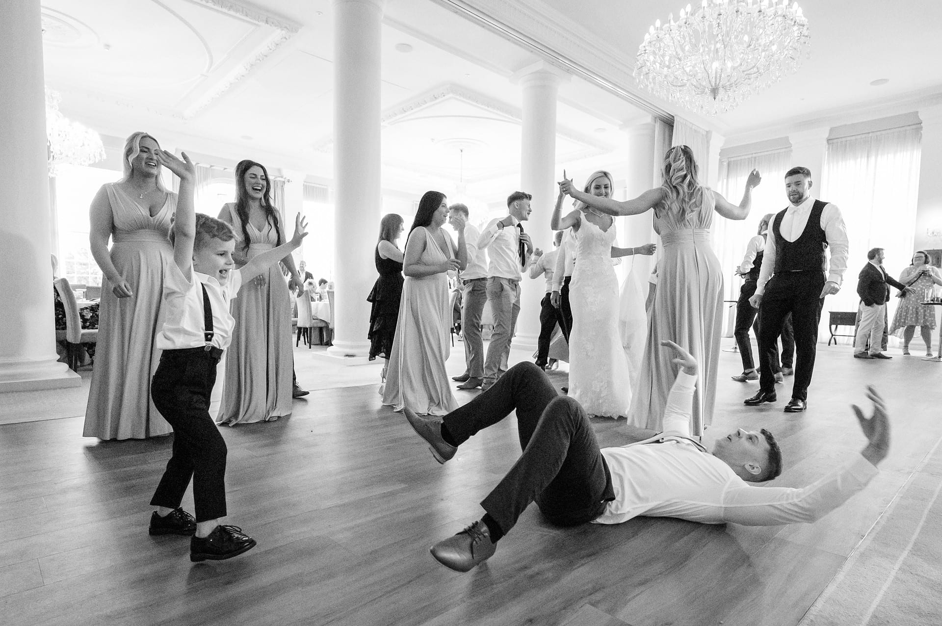 Pageboy taking a run to balance on top of a wedding guest is laying on the floor ready to catch him