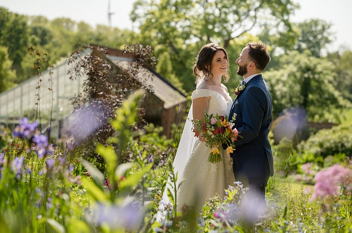 Bride and groom looking romantic in a walled garden full of spring flowers
