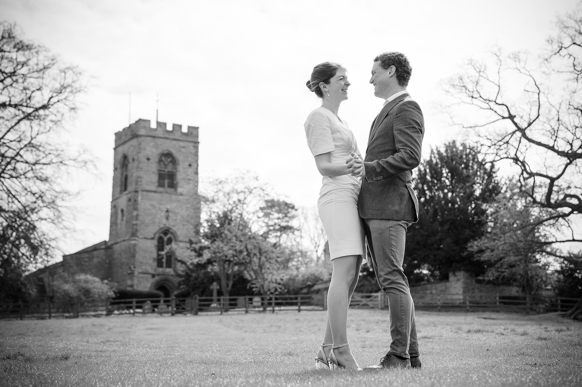 Engaged couple standing in front of Courteenhall church