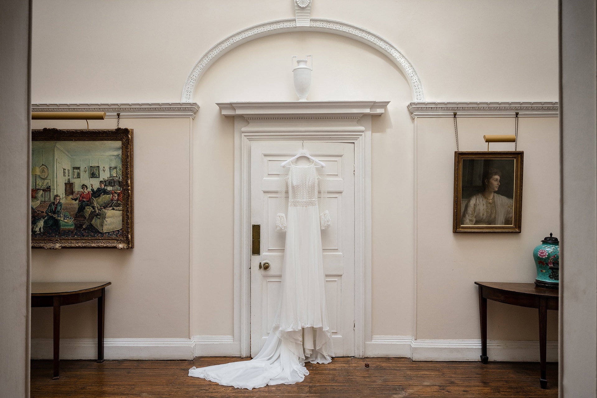 Bride's dress hanging on a door in a country house bedroom corridor