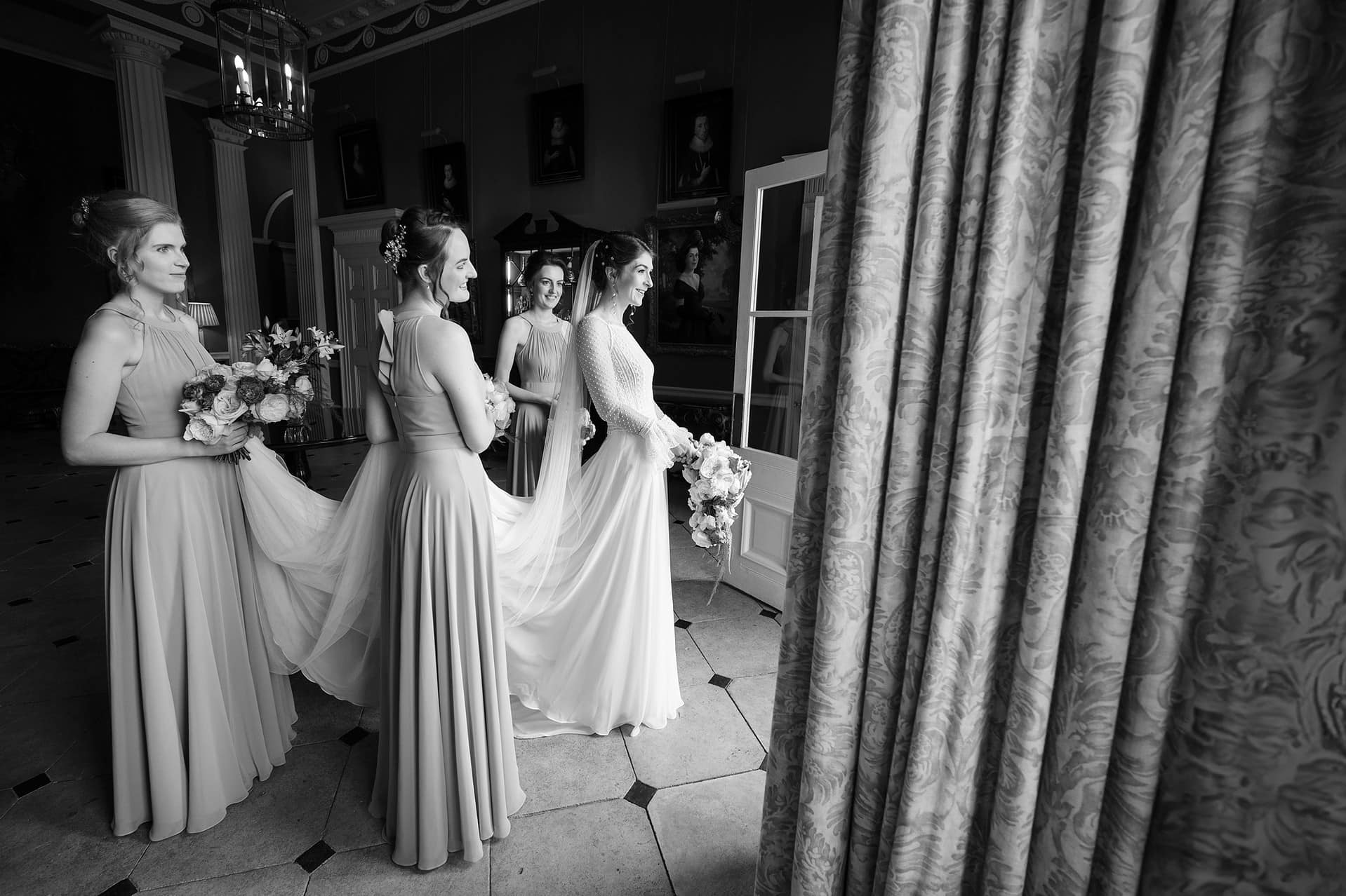 Bride and her bridesmaids about to walk out the door at Courteenhall to head to the church