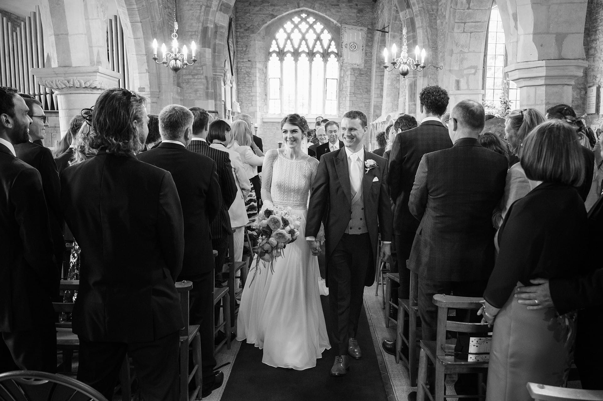 Bride and groom walking down the aisle at Courteenhall church