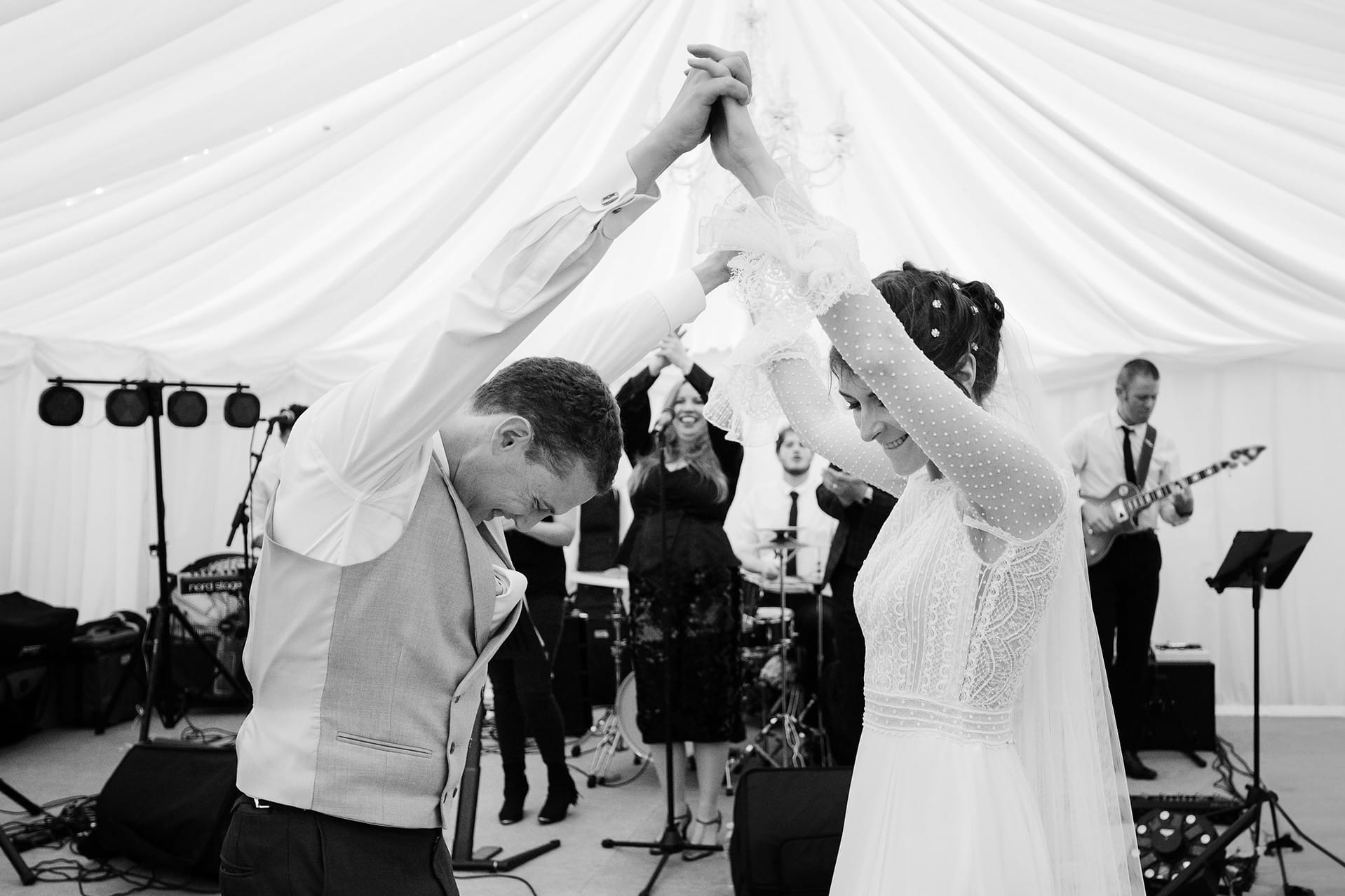 Bride and groom with their arms in the air doing a fast first dance