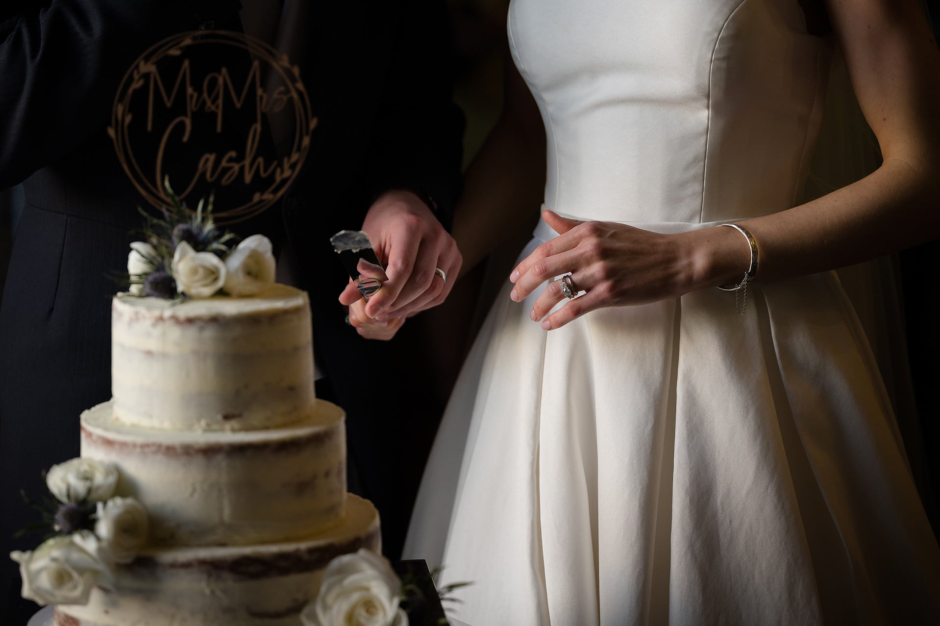 Close up of the bride and groom's hands just after cutting their wedding cake with the knife still in the groom's hand