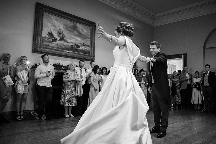 The groom smiling at the bride as he twirls her around during their first dance