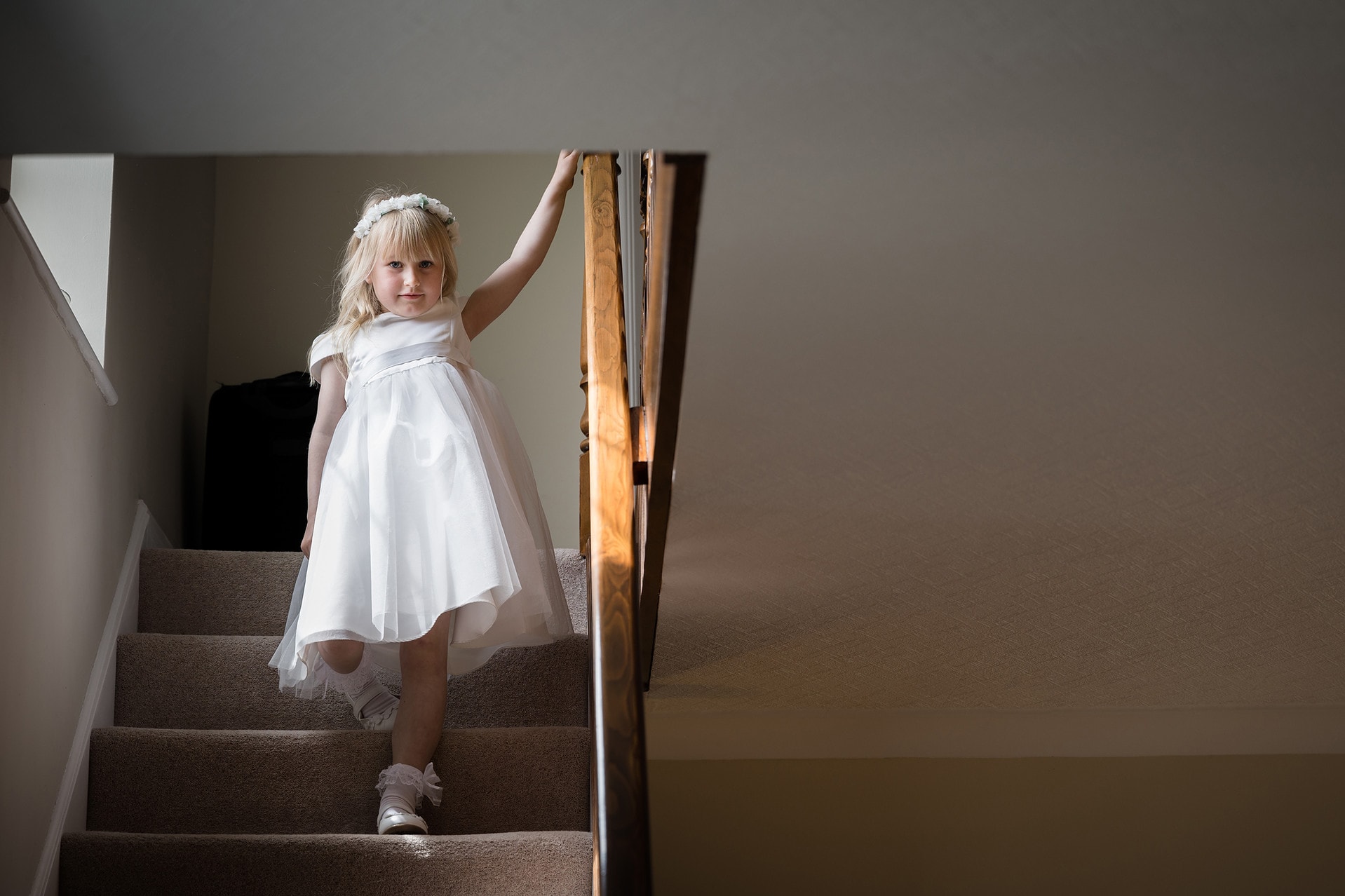 Flower girl stopping to look at the camera as she walks down the stairs