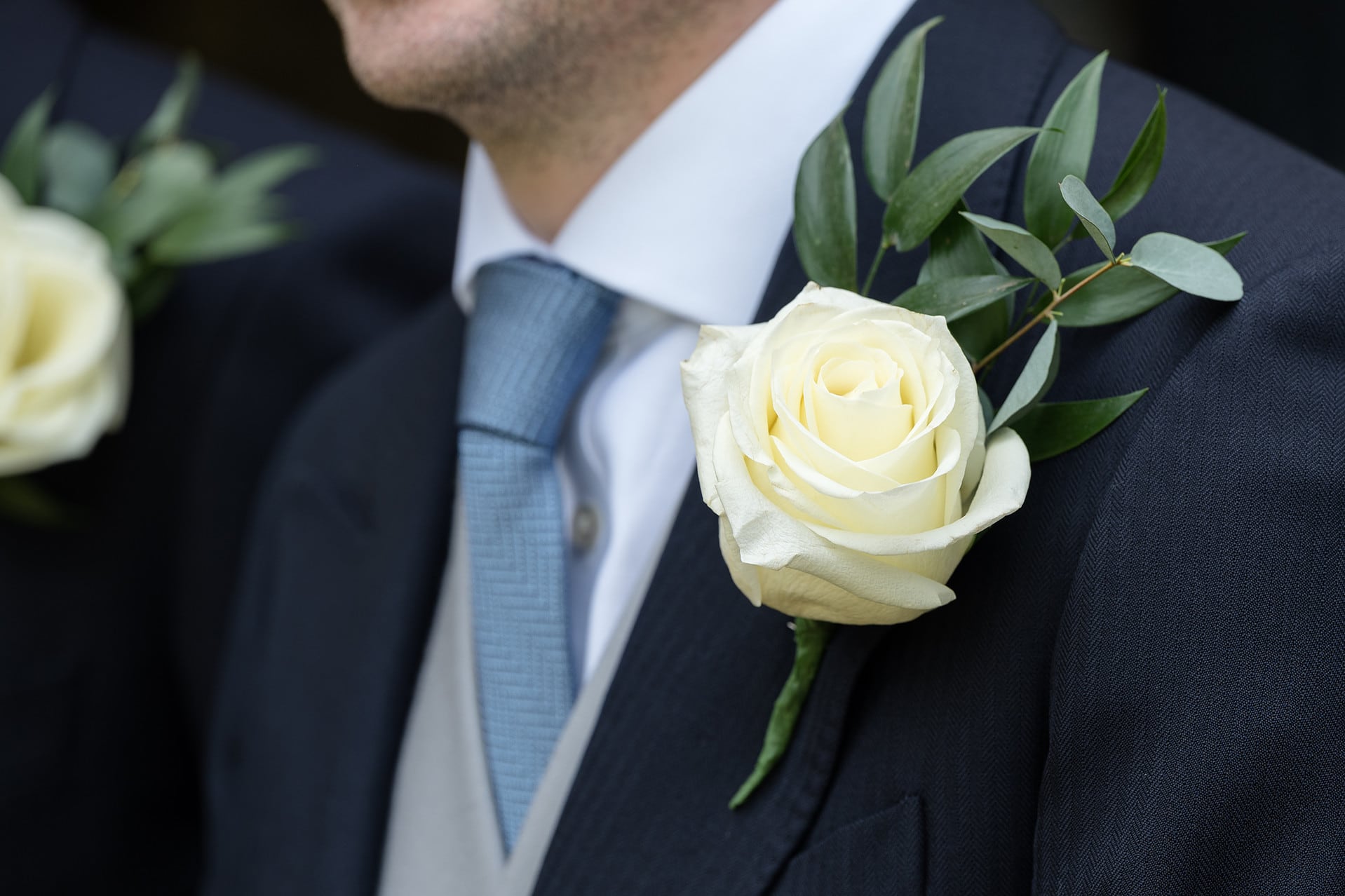 A close up of a white rose and foliage buttonhole