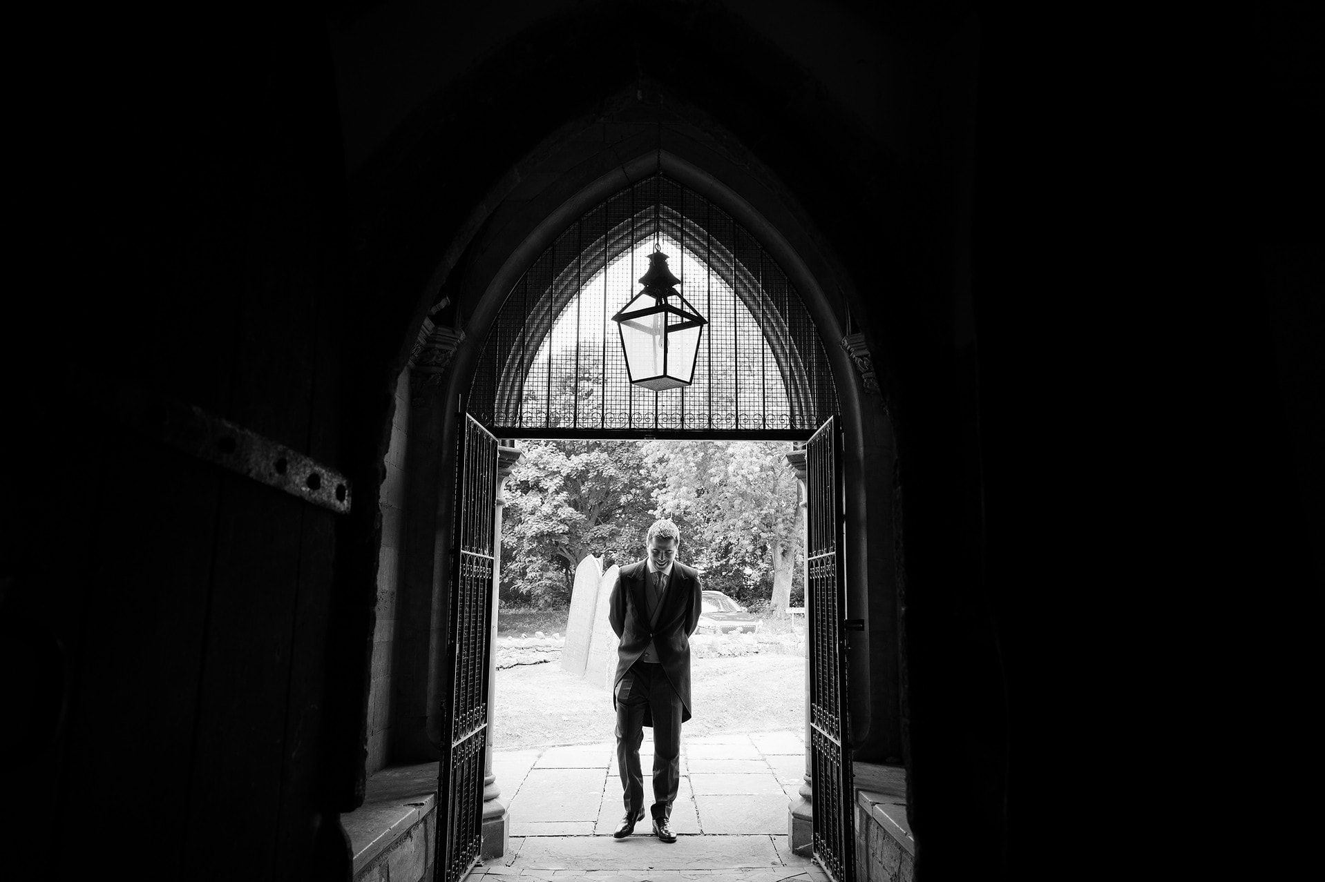 A silhouette of the groom standing in the church doorway waiting for guests to arrive