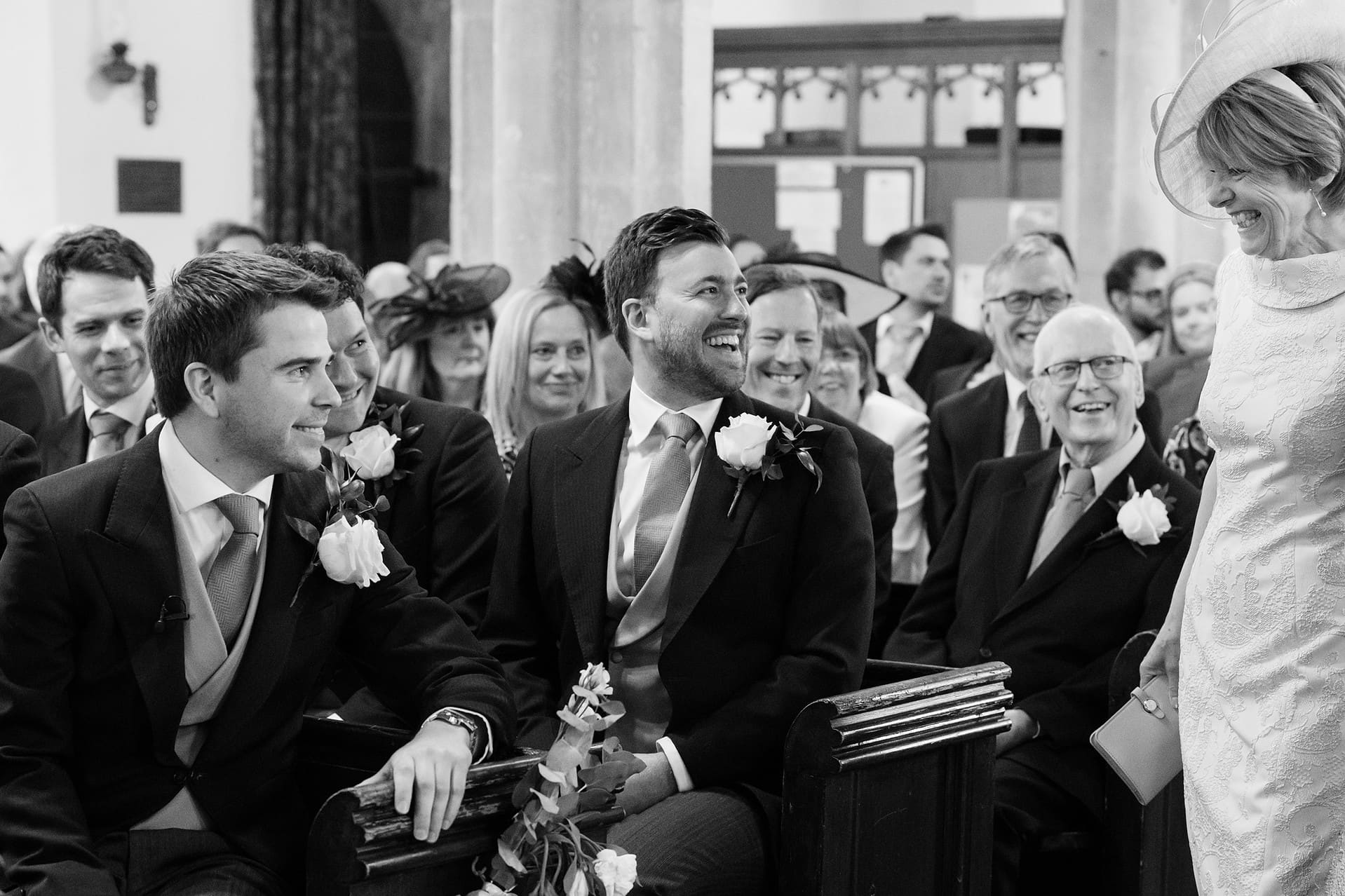 The groom and best man reacting to the bride's mum walking down the aisle