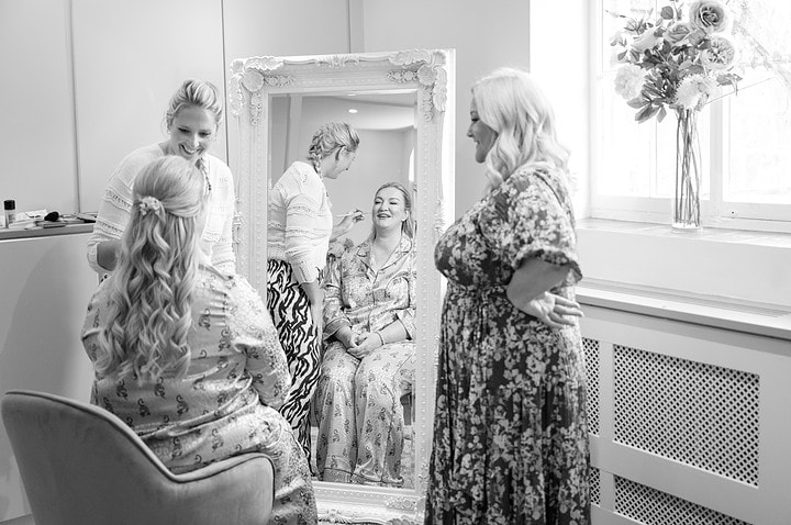 A bride wearing PJs as she has her makeup done in the wedding suite at Kelmarsh Hall