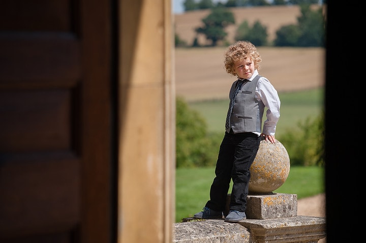 A young child sitting on a stone finial on the entrance steps to Kelmarsh Hall