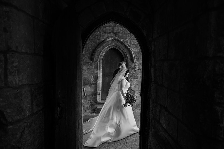 Bride and groom walking under the gate lodge at Rockingham Castle