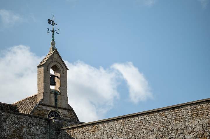 A close up photo of a bell and weather vane at Rockingham Castle