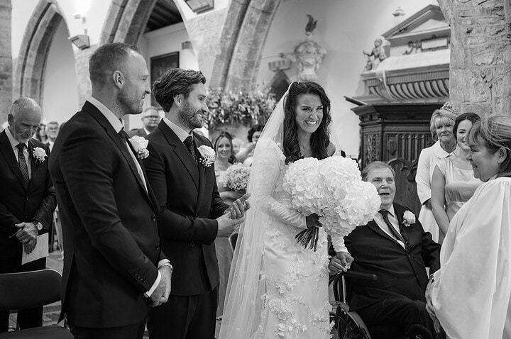The bride reaches the groom at the altar at Fawsley church