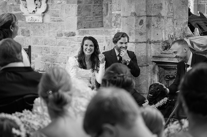 The bride, groom and even their dog with shocked expressions on their faces as the vicar makes a joke during their address
