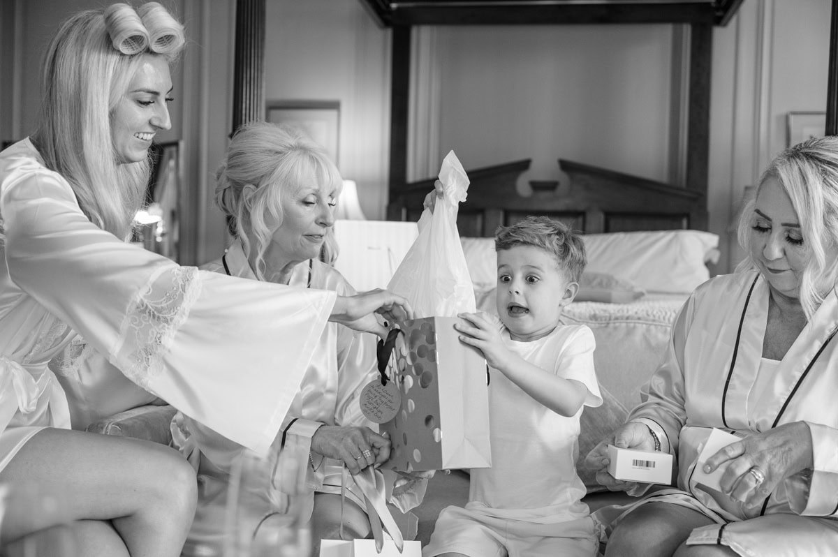 Page boy's excited and surprised face as he opens a gift from the bride